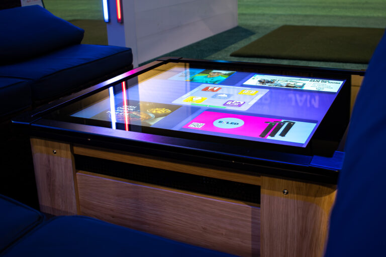 Bay Station touchscreen table displaying interactive content in a golf driving range bay