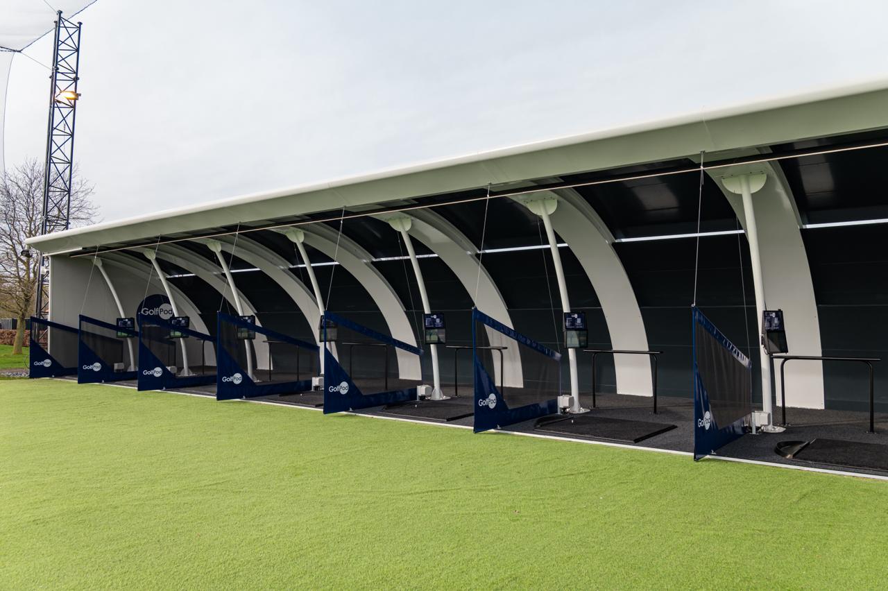 Covered Golf Pod driving bays beside the practice outfield